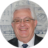 Image of an older business man in a black suite and white button-up while wearing glasses